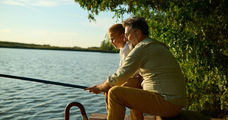 A grandfather teaches his grandson to fish