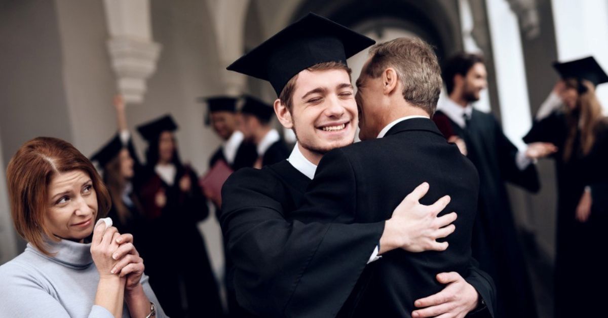 A young graduate hugs his father