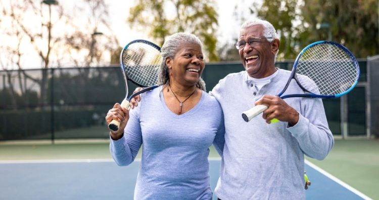 An older couple play tennis together.
