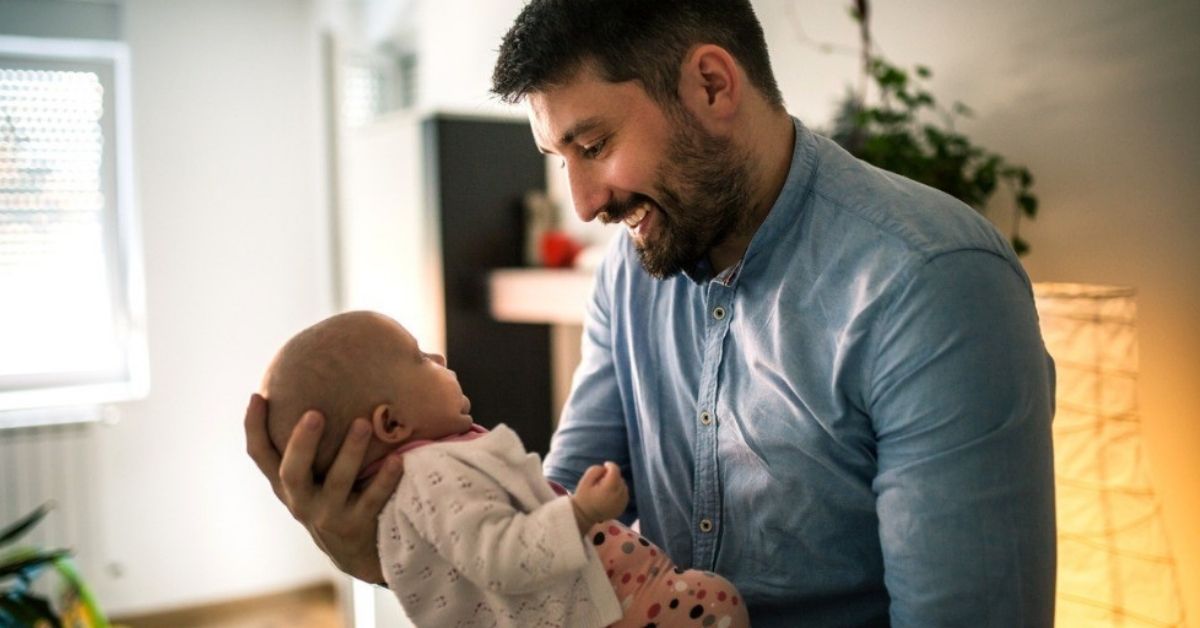 A young father holds his baby