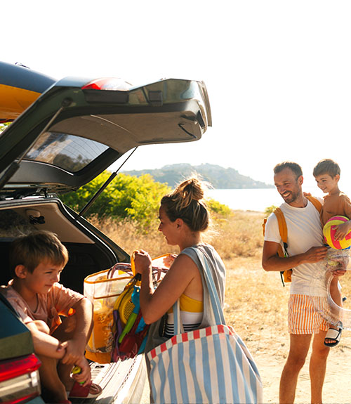 Family with two children unloading car at the beach