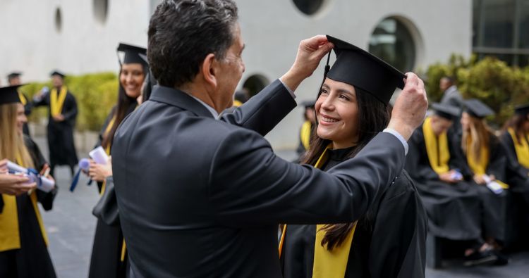 A father adjusts his daughter's graduation cap.
