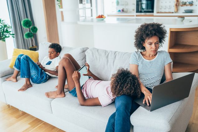 A single mother on her laptop next to her children.