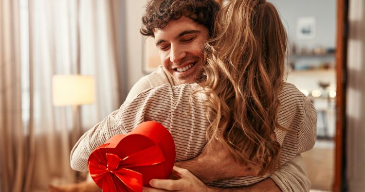 An couple embrace while holding a Valentine's Day card