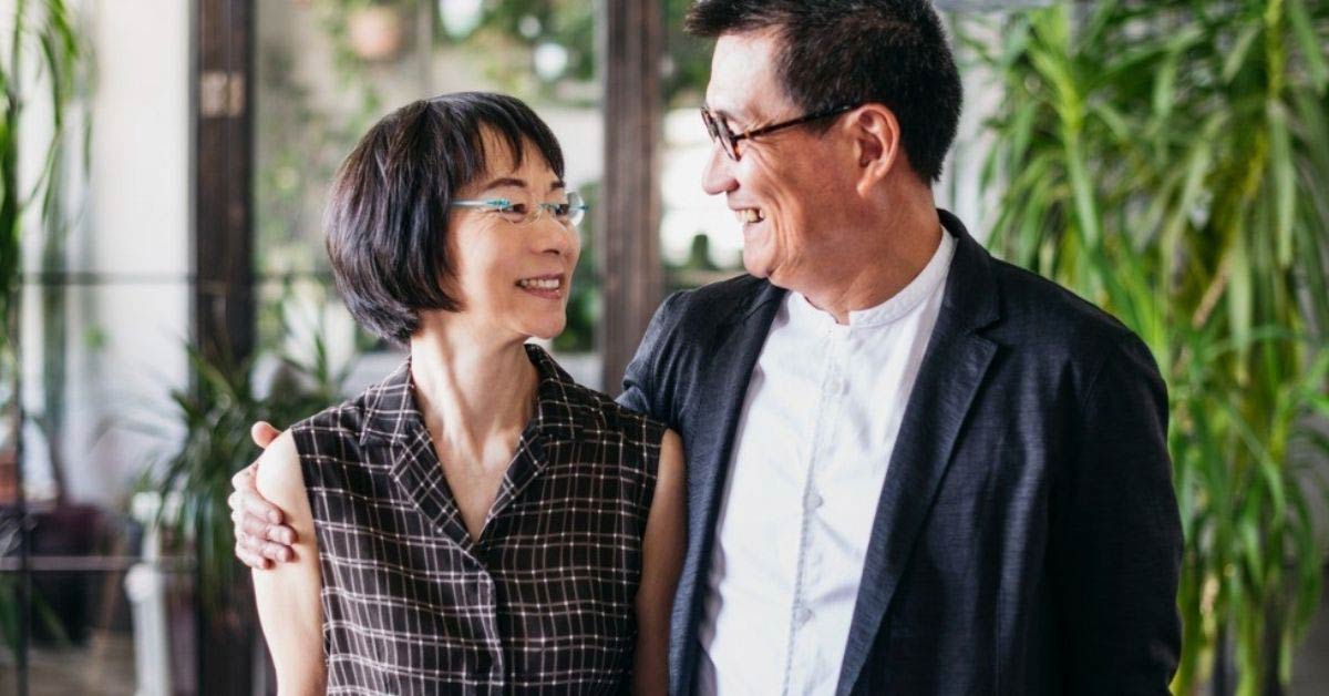 A retired couple smile while looking at each other
