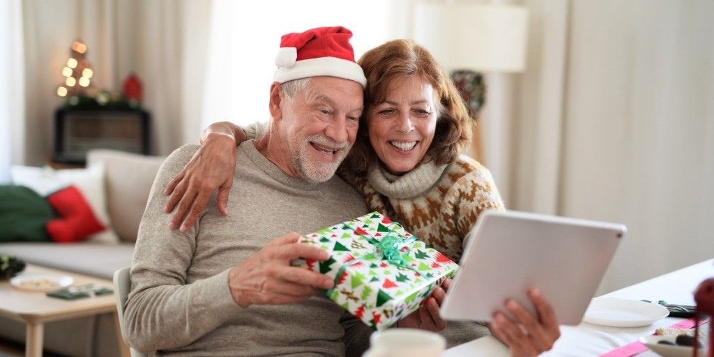 An older couple wearing holiday clothes video chats with their family