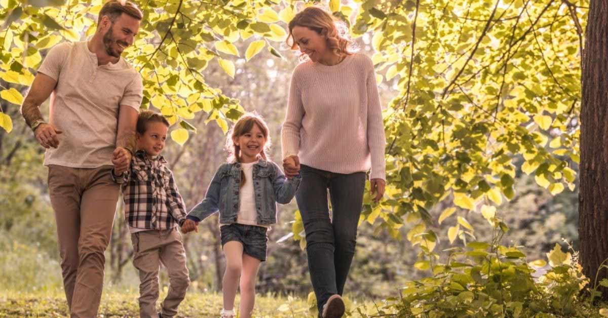 A young family walk hand-in-hand through the woods