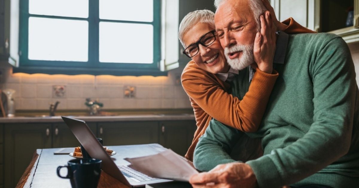 An older couple embrace while researching retirement planning advice