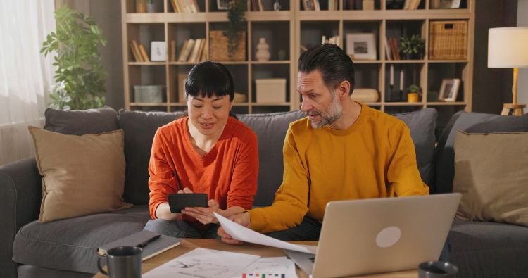A couple reviewing financial documents and a calculator together at home
