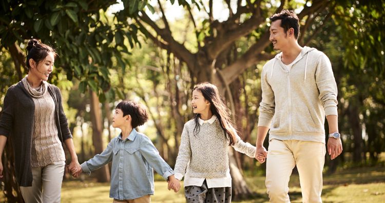 Asian family walking outside while holding hands