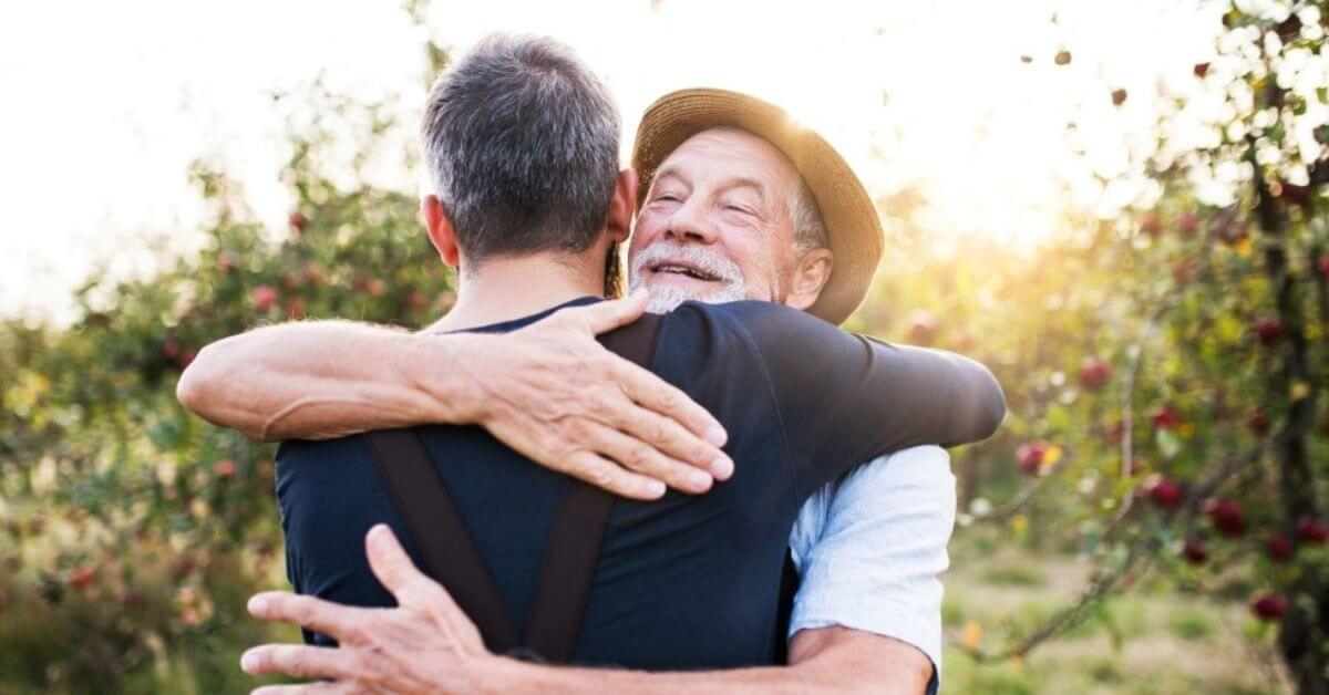 A man hugs his adult son.