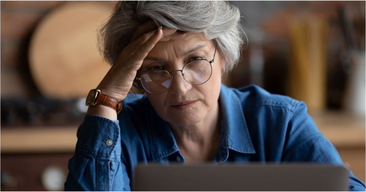 A retired woman looks concerningly at her computer.