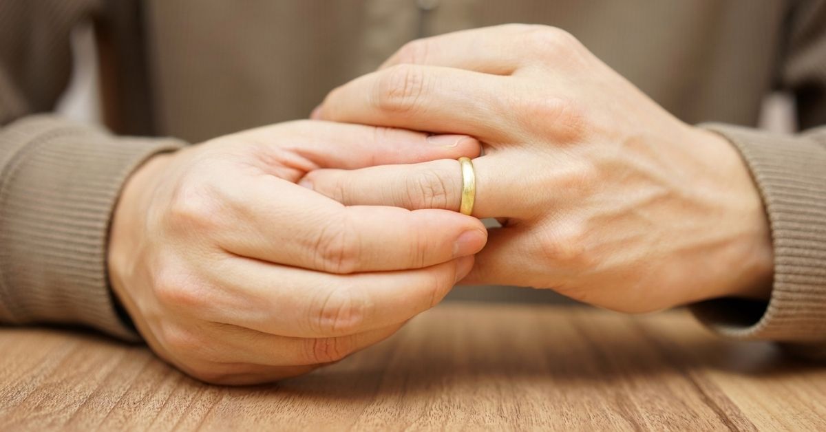 A person takes their wedding band off their finger