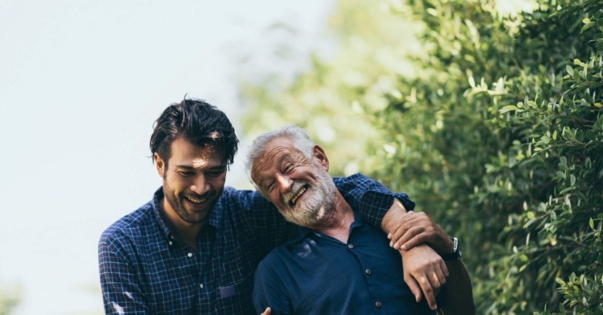 A young man wraps his arms around his father's shoulders.