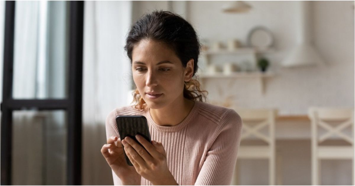 A woman looks curiously at her phone.