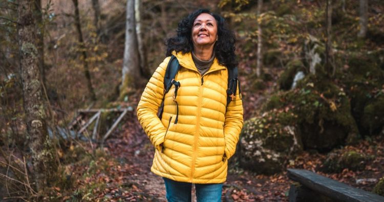 Woman in yellow jacket walking in the woods