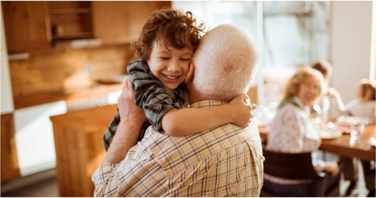 A grandchild gives his grandfather a big hug.