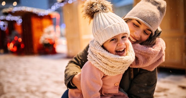 A mom and her young daughter enjoy the snow together