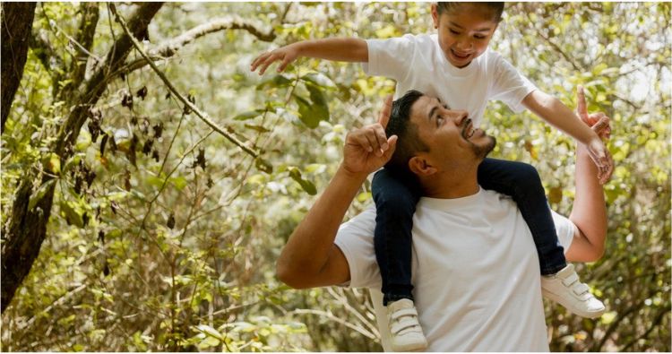 A father carries his young daughter on his shoulders.