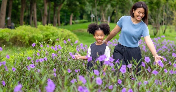 A mother walks ina field of violets with her young daughter