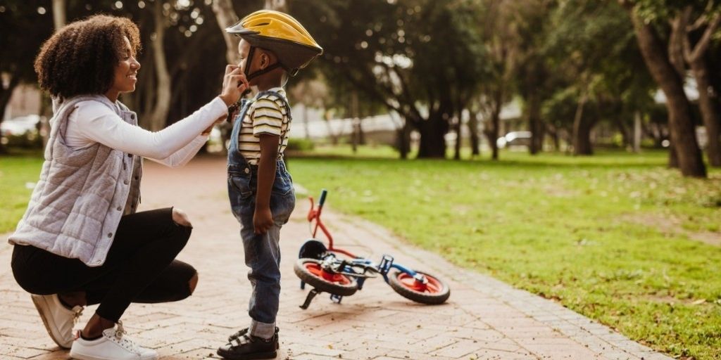 A young mother secures a bike helmet on her son.