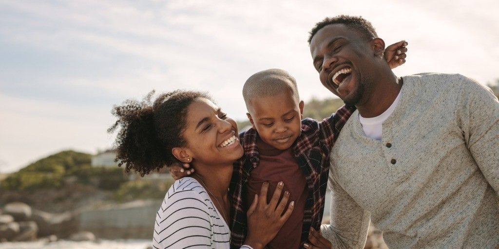 A young family flash big smiles while having a good time at the beach