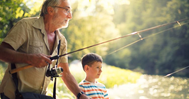 A grandfather casts a line teaching his grandson how to fish.
