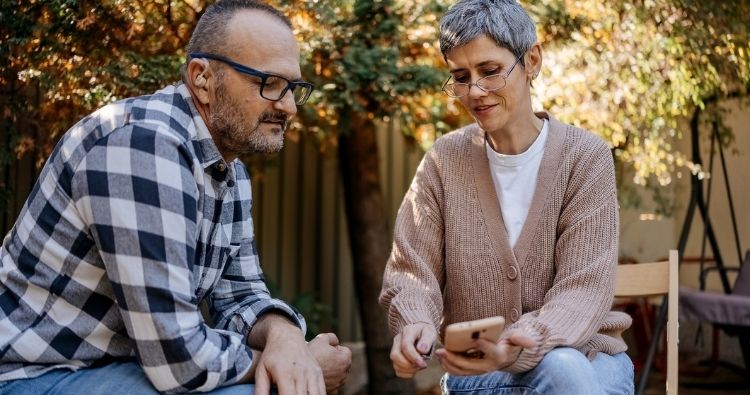 Couple reviewing retirement savings on a phone outdoors