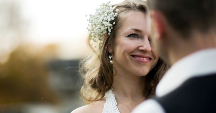 A young bride smiles at her groom in the foreground