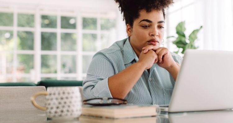 A young woman looks curiously at her laptop