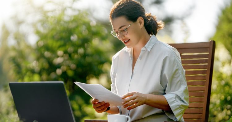 A woman works on her laptop outside.
