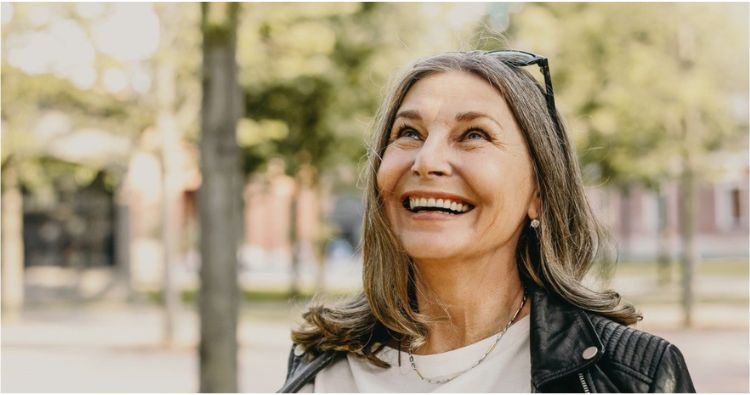 A retired women looks up with a big smile.