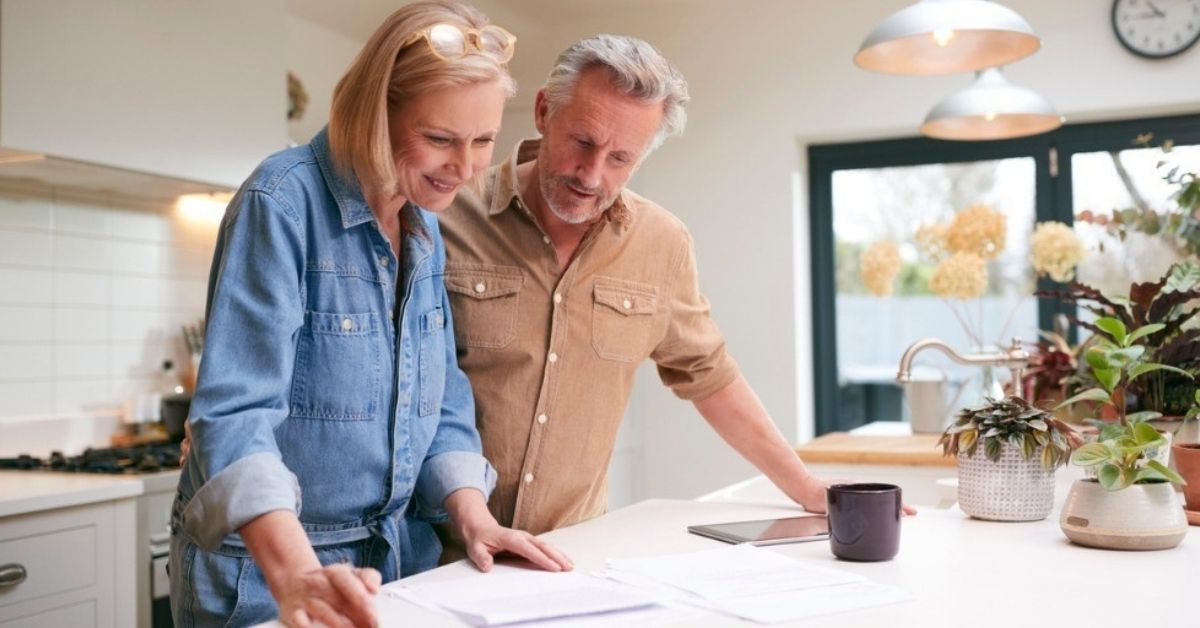 An elder couple look over their retirement documents in their kitchen