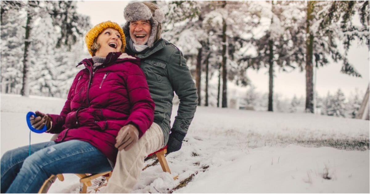 Am older couple laughs while riding a sled in the snow