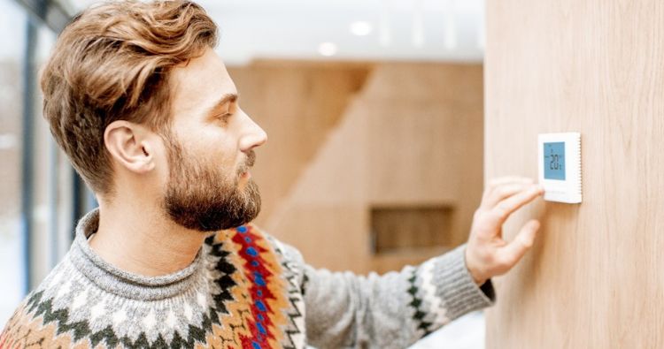 Man adjusting the temperature on thermostat