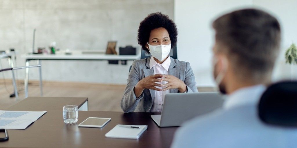 A women in a face mask has a business meeting with a man