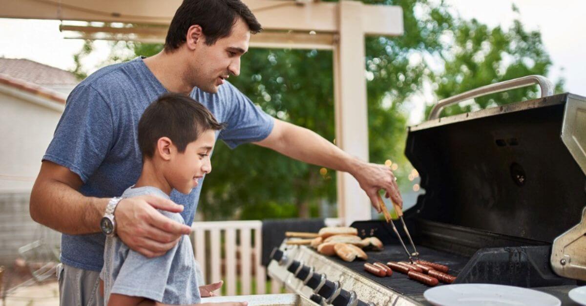 A dad enjoys a summer night grilling with his son.