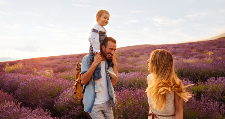 A young family walks through a field of lilacs