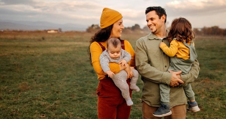 A young family talk a walk together in a field.