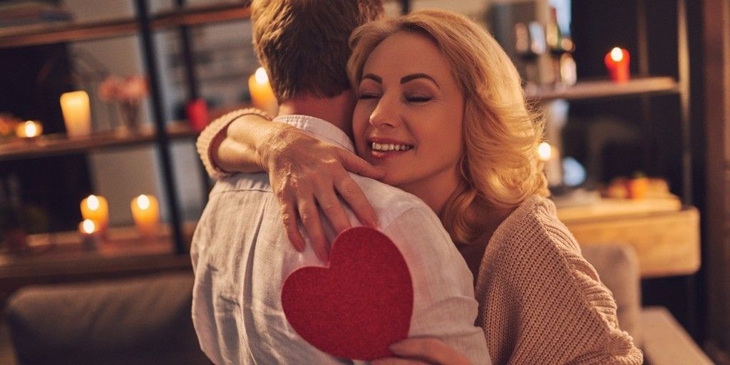 An older couple embrace while holding a Valentine's Day card