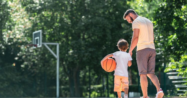 A young father plays basketball with his son