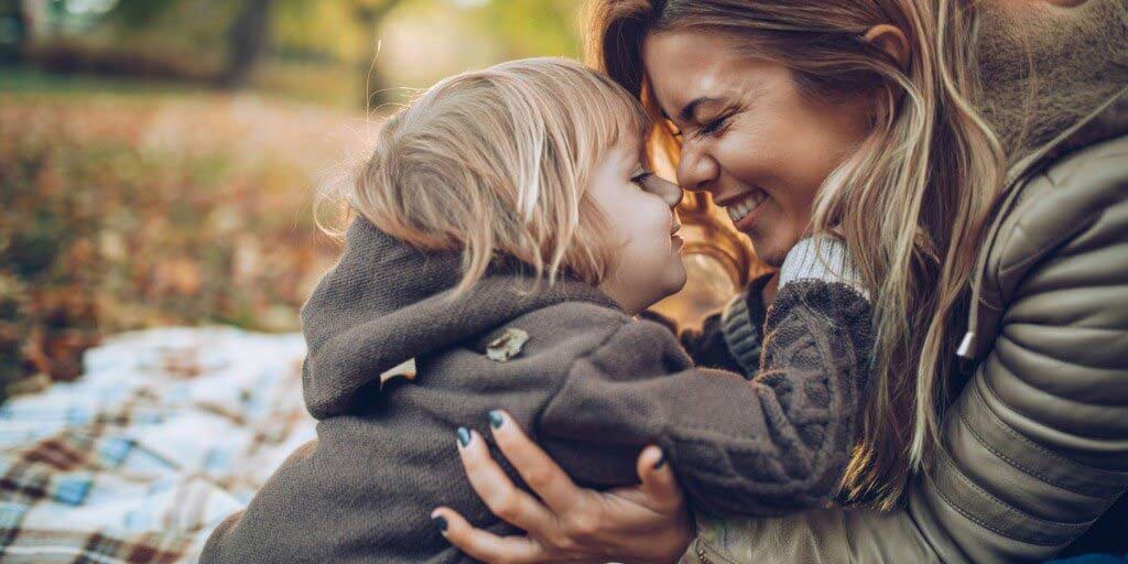 A white woman gives and eskimo kiss to her young son.