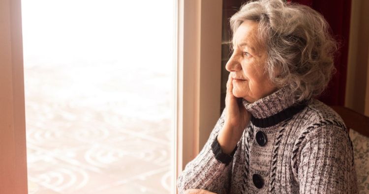 A woman looks out her window at a winterscape.