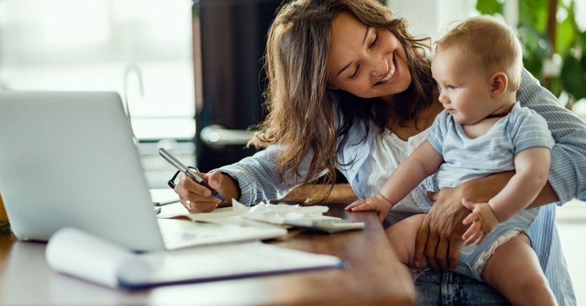 A young mom holds her baby while working