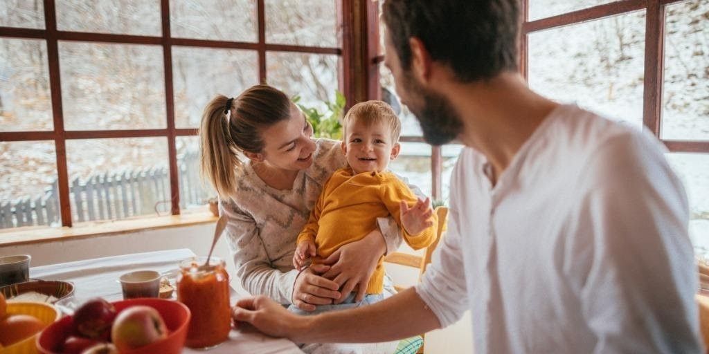 A young family prepares breakfast together in their kitchen